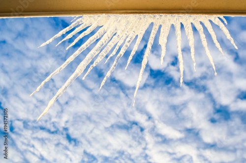 Semicircle of Large Sparkling Icicles on Window Frame at Sky