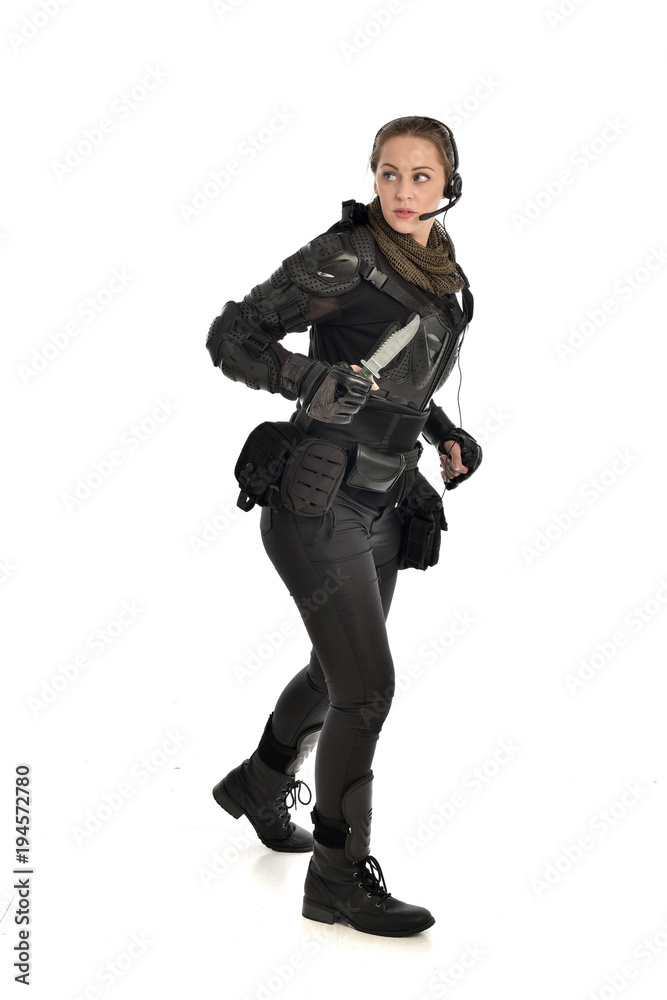 full length portrait of female soldier wearing black tactical armour, holding a remote knife, isolated on white studio background. full length portrait of female soldier wearing black tactical armour, holding a remote knife, isolated on white studio background.