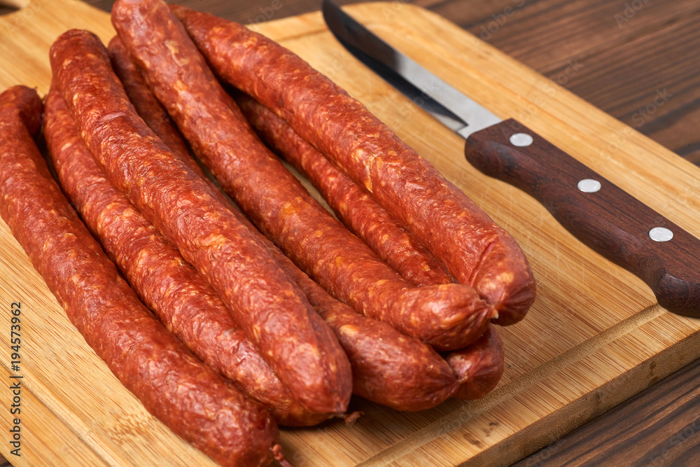 Thin smoked sausage on a wooden background. Close-up.