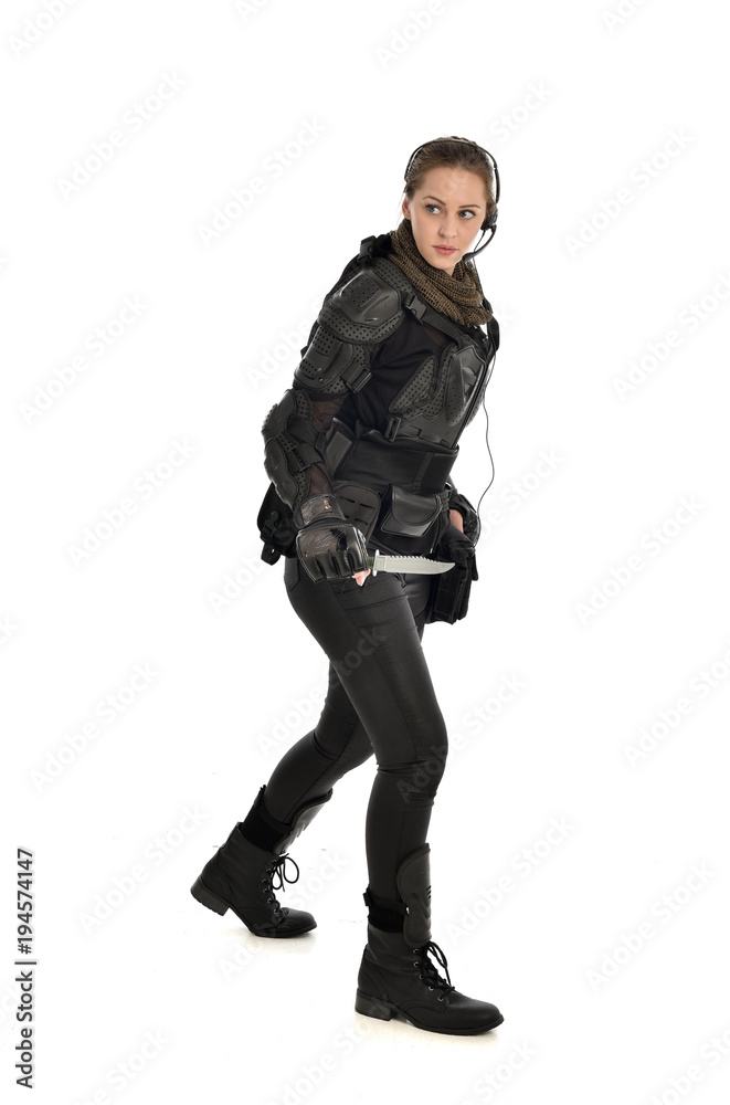 full length portrait of female soldier wearing black tactical armour, holding a remote knife, isolated on white studio background. full length portrait of female soldier wearing black tactical armour, holding a remote knife, isolated on white studio background.