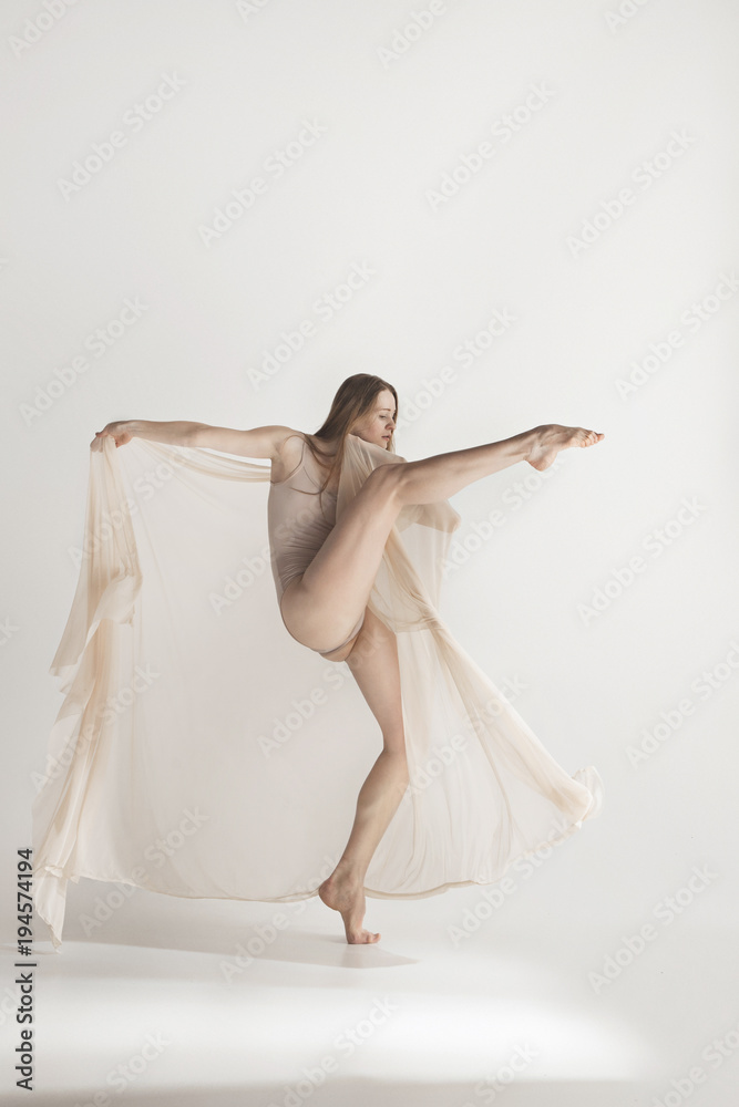Fototapeta premium Young beautiful dancer in beige swimsuit dancing on gray background