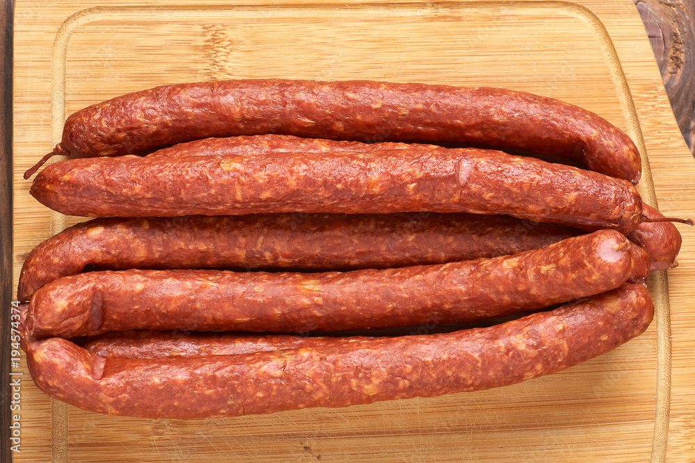 Thin smoked sausage on a wooden background. Close-up. Thin smoked sausage on a wooden background. Close-up.
