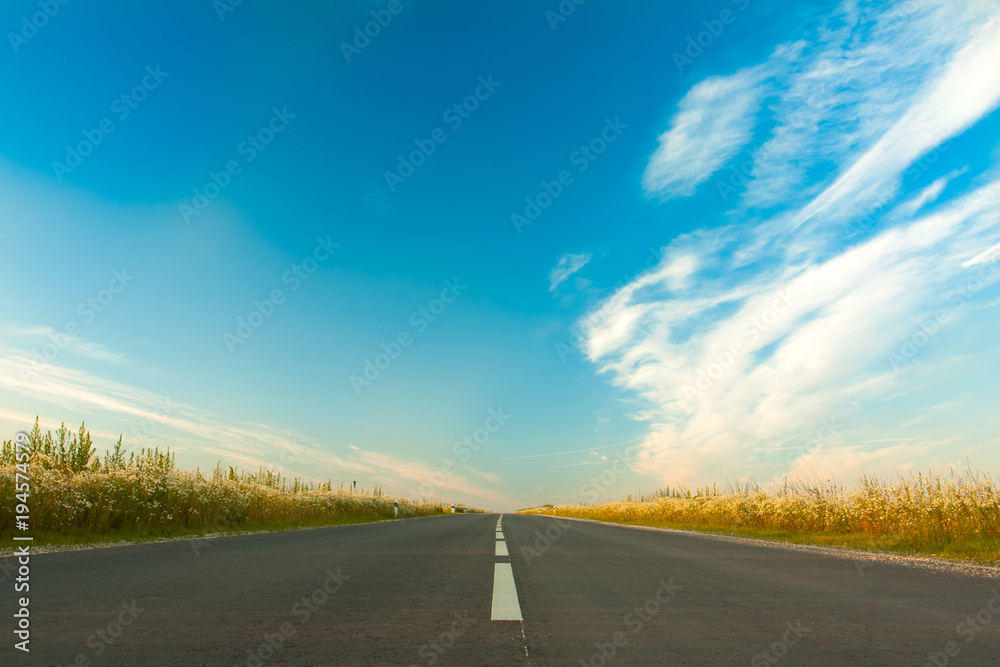Wide Asphalt Gray Road On Bright Blue Sky Background With Clouds In Spring.
