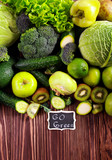 Green vegetables and fruits over wooden background