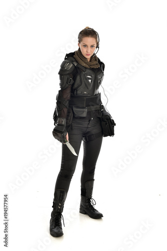 full length portrait of female  soldier wearing black  tactical armour, holding a remote knife, isolated on white studio background. © faestock