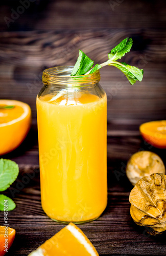 healthy orange cocktail with mint leaves in bottle on kitchen ba