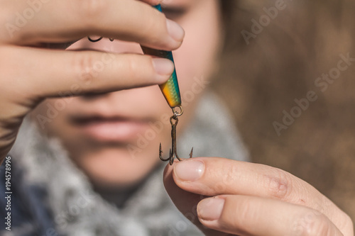 Girl preparing a hook for fishing.