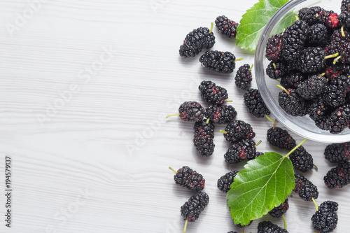 Mulberry and leaves on a white wooden background Top view with space for text