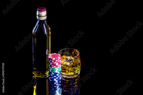 Bottle with glass of whiskey and poker chips