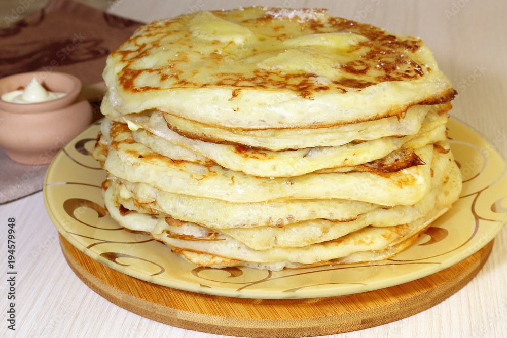 Food. Appetizing baked thick yeast pancakes are stacked on a plate on the table.