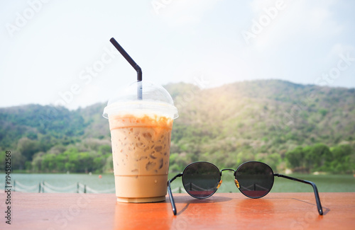 Cool coffee and sunglasses are placed on the table. The mountain and river.