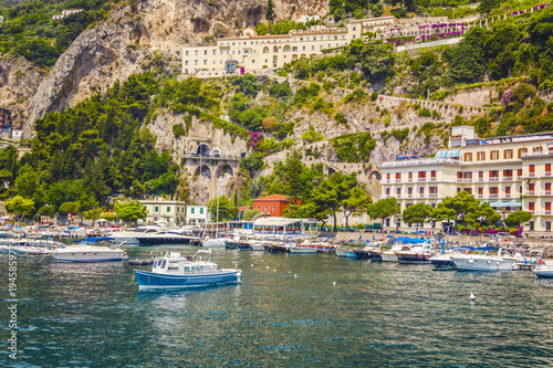 View from the sea on the beautiful architecture of the city of Amolphi and a small bay with white boats and yachts at famous Amalfi Coast with Gulf of Salerno, Campania, Italy photo