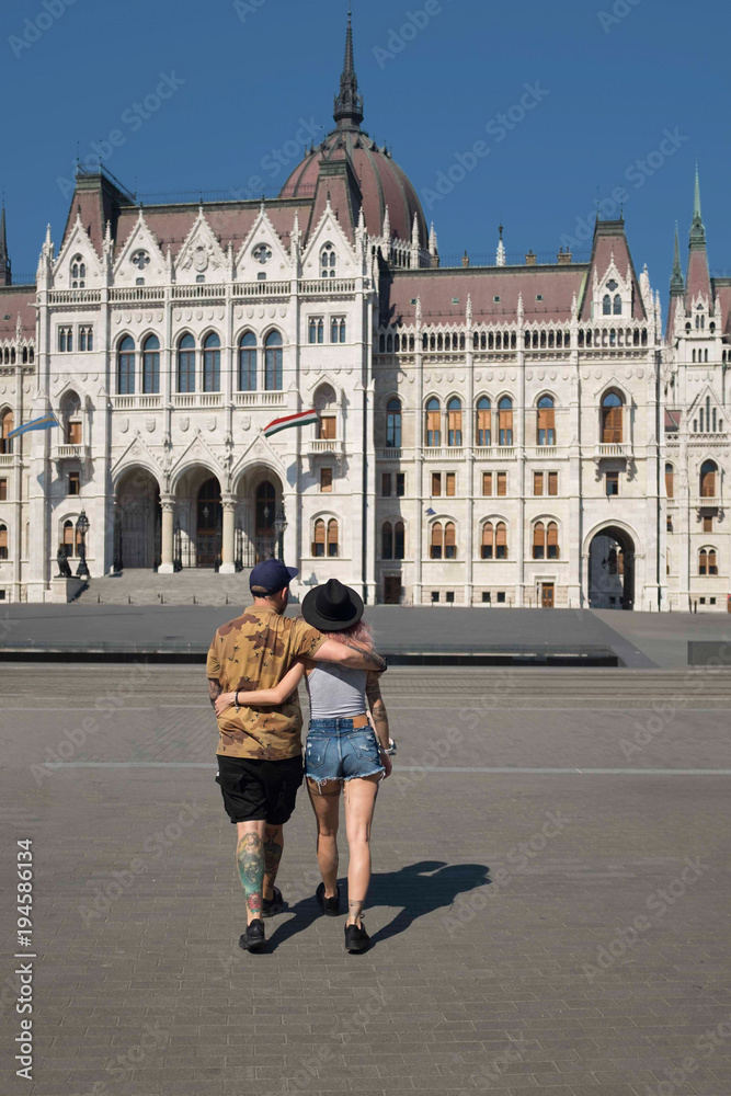 back view of young couple embracing and walking near parliament building in budapest