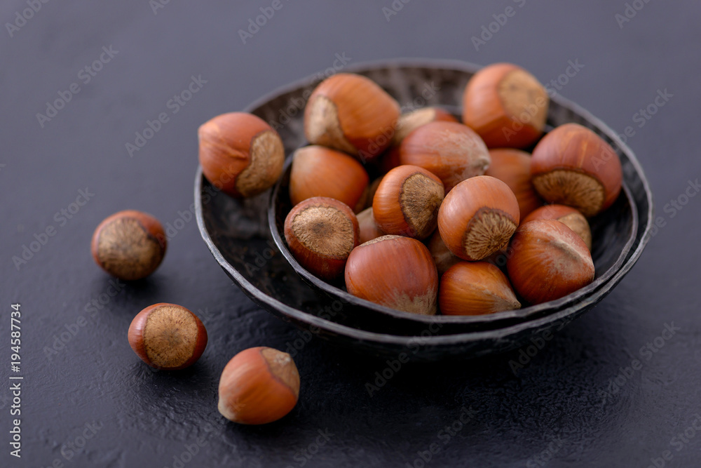 Hazelnuts for healthy snack in plate and scattered on table Hazelnuts for healthy snack in plate and scattered on table