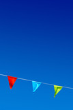 Three colorful party flags blowing in the wind against blue sky.