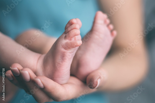 the legs of the baby in the hands of the mother