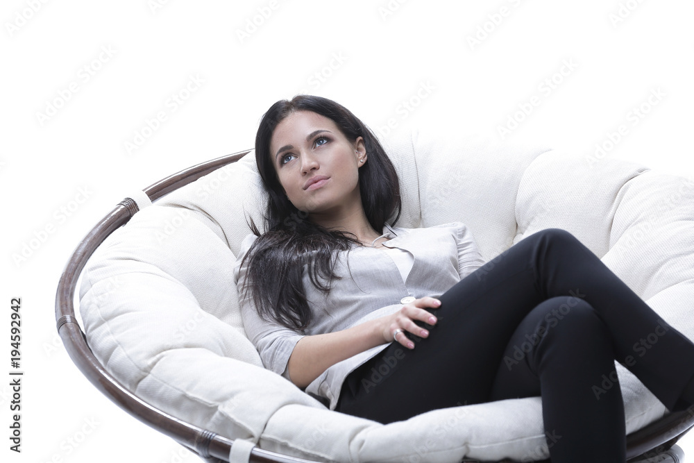Modern young woman sitting in a round cozy soft chair Modern young woman sitting in a round cozy soft chair