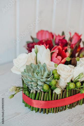 Romantic luxury flower arrangement with white roses  pink tulips  succulent plant and eucalipt with red ribbon.