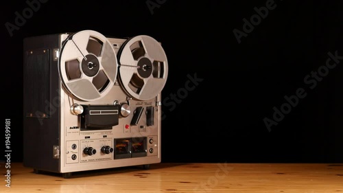 Reel to Reel tape recorder playing music isolated on black bakcground and space for copy