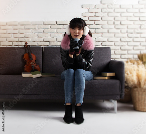 Lady with blue jean and leather jacket is sitting on sofa and posing in relax acting
