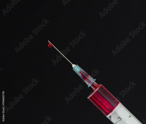 Obraz na płótnie Syringe with a drop of blood on a needle on a black background w salonie
