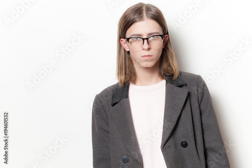 Androgyne young man with coat on white background. Studio portrait