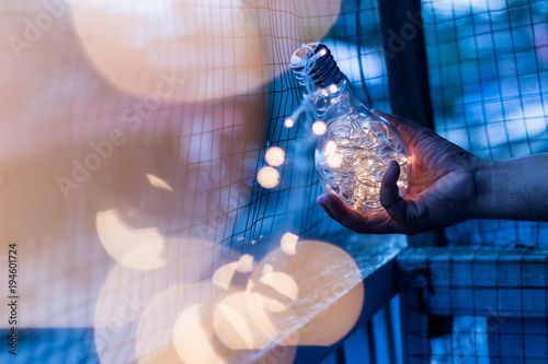 Garland light in a glass bottle, placed the hands of man in the evening. In the light concept in hand