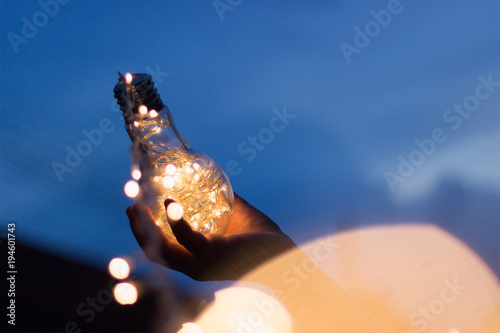 Garland light in a glass bottle, placed the hands of man in the evening. In the light concept in hand