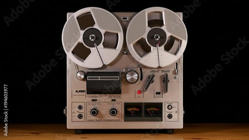 Vintage Reel to Reel tape recorder playing music isolated on black background