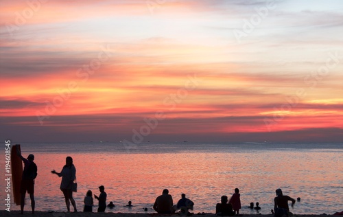 Silhouettes of people on the beach gesticulating,swimming, watching the sunset
