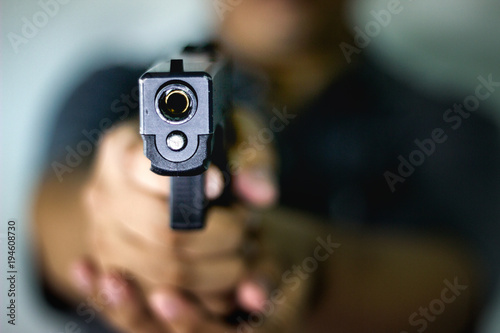 A man holding a gun pointing to a target demonstrates the violence of a gun with blurry background © ketchana