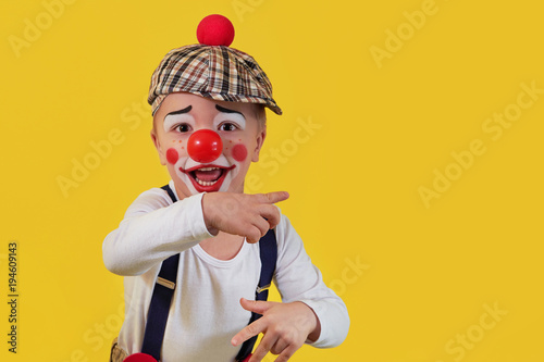 Fotografie, Obraz Child clown smile shows a finger copy space area on yellow background