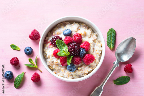 Photo Oatmeal cereal with milk and berries top view.