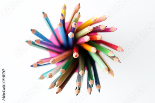 Bunch of multicolored pencils in the plastic glass on white background, view from top