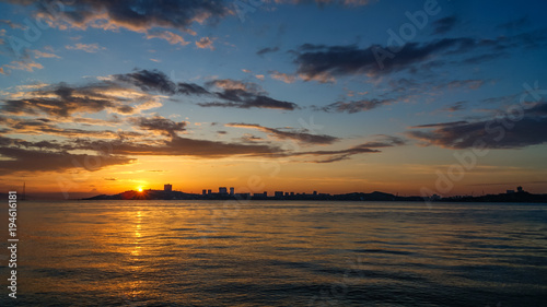Beautiful sunset on a sea, urban buildings on the bank