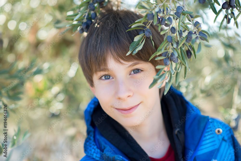 Handsome boy posing in olive trees garden. Kid's portrain over mediterranean olive field ready for harvest. Smiling teen boy in spanish olive's grove with ripe fresh olives. Handsome boy posing in olive trees garden. Kid's portrain over mediterranean olive field ready for harvest. Smiling teen boy in spanish olive's grove with ripe fresh olives.
