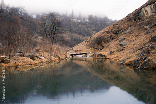 Gloomy quiet pond in a mountainous area with fog. © terentiewshura
