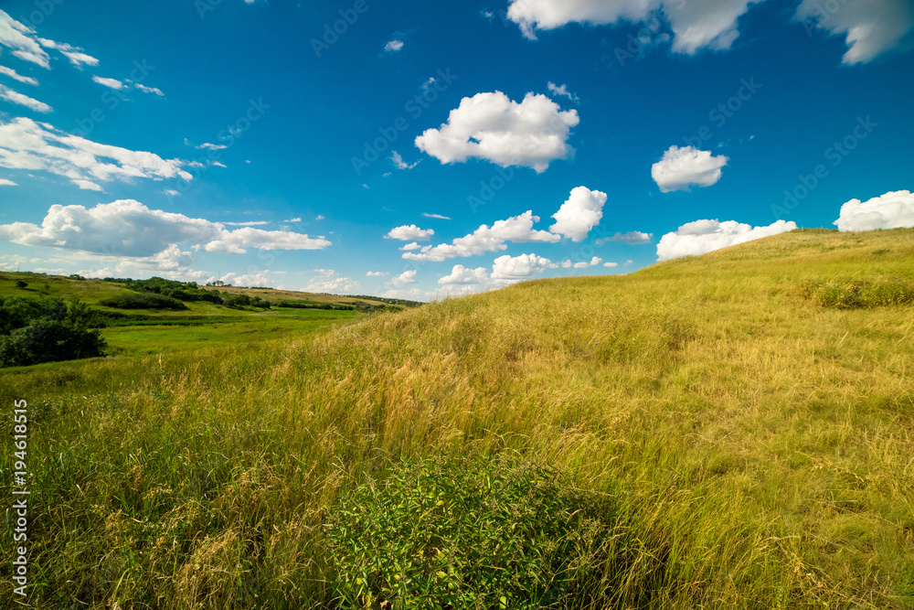a summer landscape of rolling hills with beautiful clouds