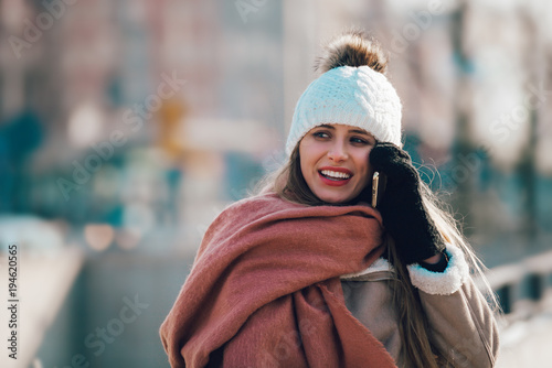 Young woman in the city street using mobile phone at winter time