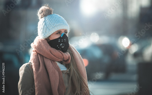 Young woman wearing protective mask in the city street, smog and air pollution photo