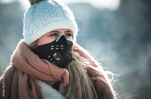 Plakat Young woman wearing protective mask in the city street, smog and air pollution