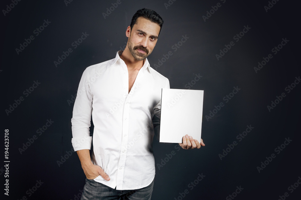 Young man in white shirt reading a booklet Young man in white shirt reading a booklet