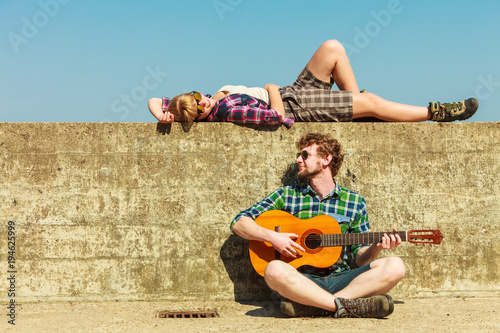 Young man playing guitar to his girlfriend by seaside
