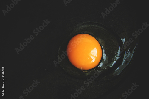 raw egg with yellow egg broken into a frying pan