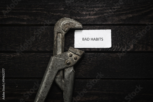 Photography pipe wrench compresses a piece of paper with an inscription bad habits