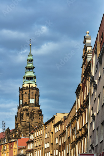 Houses and a gothic church tower with a clock in the city of Swidnica.