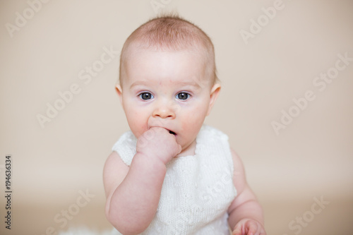 Close portrait of cute little baby boy, isolated on beige background, baby making different facial expressions
