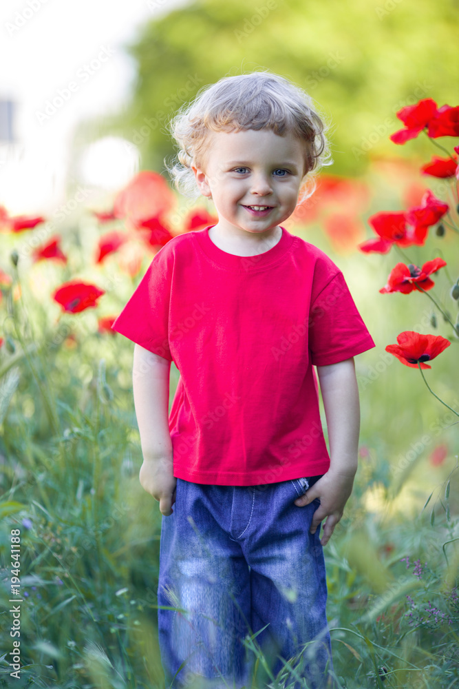 A small blond boy is holding red poppy flower A small blond boy is holding red poppy flower