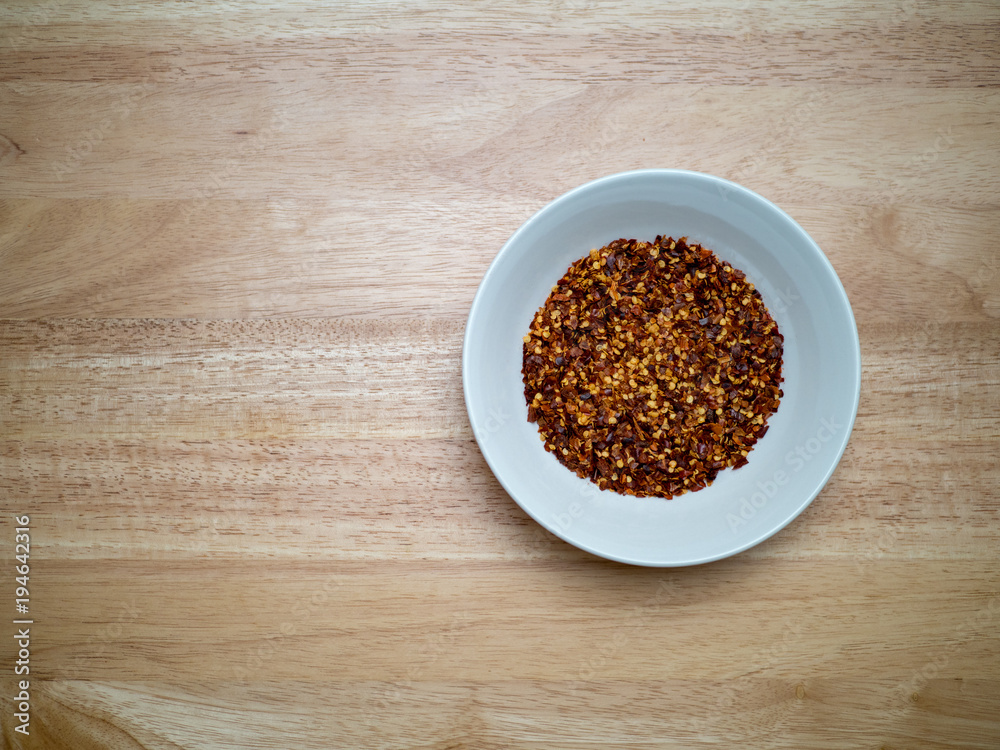 Overheard shot of porcelain bowl filled with red pepper flakes Overheard shot of porcelain bowl filled with red pepper flakes