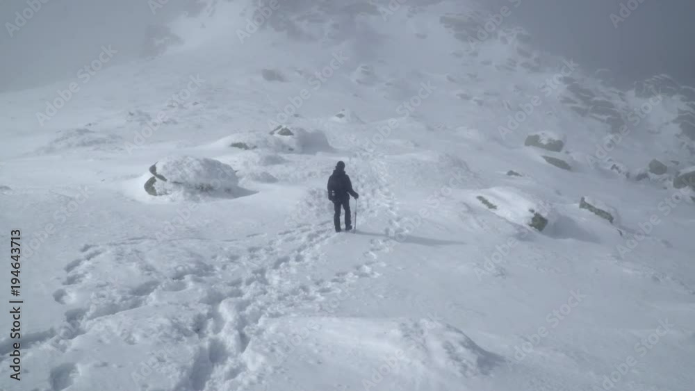 Hiker approaching snowy mountain peak Hiker approaching snowy mountain peak